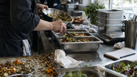 Caterer portioniert Speisen in Gastronorm-Behälter